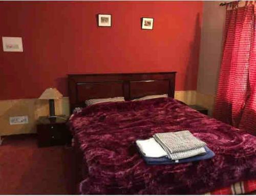 a red bedroom with a bed with two towels on it at Well-equipped modern flat with 24/7 security in Srinagar