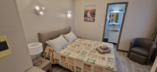 ein kleines Schlafzimmer mit einem Bett und einem Stuhl in der Unterkunft Le Faubourg in Figeac