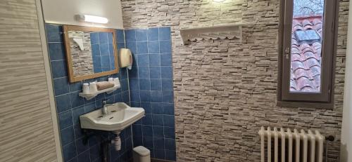 a blue tiled bathroom with a sink and a mirror at Le Faubourg in Figeac