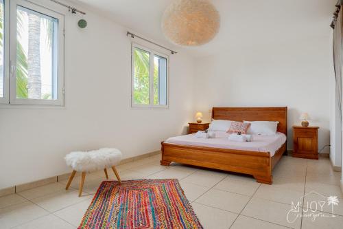um quarto com uma cama, 2 janelas e um tapete em Villa Célestine, à 2 pas du lagon de la Saline em La Saline-Les-Bains