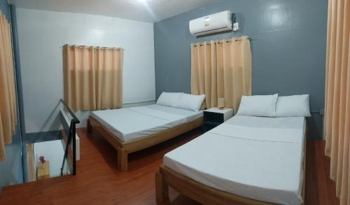 2 camas en una habitación con paredes y cortinas azules en Chico's Spacious and Private Two-Storey Home, en Zamboanga