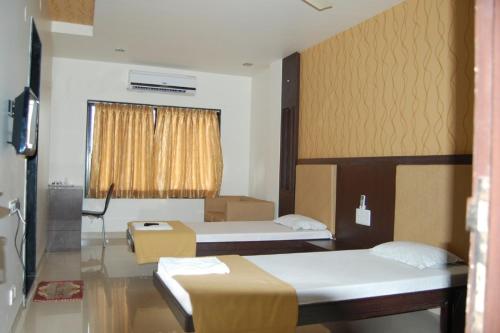 Habitación de hotel con 2 camas y TV en Hotel Sangram Palace Shirur, en Sirūr