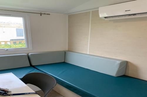 een kamer met een blauwe bank en een raam bij Camping Riva Bella in Ouistreham
