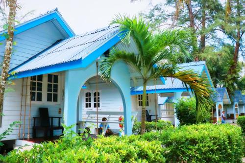 a blue house with a palm tree in front of it at PAN Beachfront Resort Krabi in Klong Muang Beach