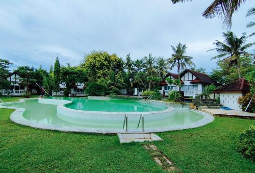 a large swimming pool in a yard with houses at RedDoorz @ Padi Beach Resort Oton Iloilo in Oton