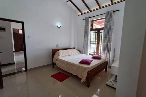 a bedroom with a bed with purple pillows on it at Spacious Greenery Homely Home in Ja-Ela