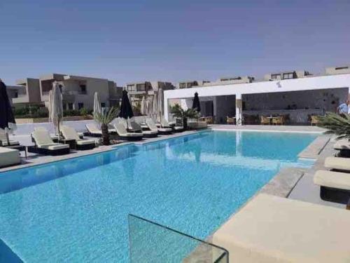 a large swimming pool with chairs and a building at Azha 2 bd chalet family only in Ain Sokhna