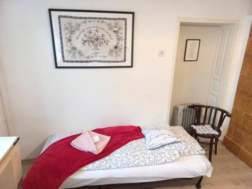 a bedroom with a bed with a red blanket on it at Lankás Vendégház - Hollókő in Hollókő