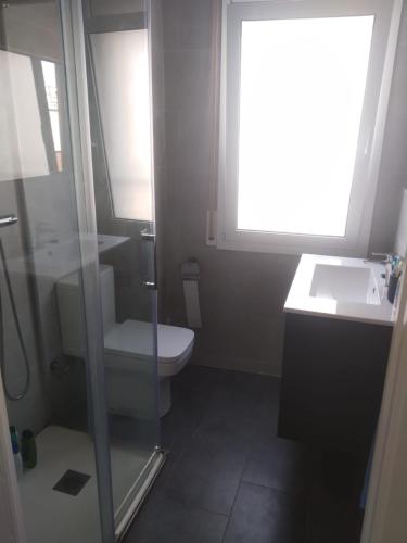 a bathroom with a toilet and a sink and a window at Baix a Mar in Torredembarra