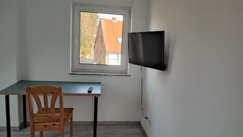 een tafel met een stoel en een televisie aan een muur bij Dammstraße 24-DG-ZV38 in Salzgitter