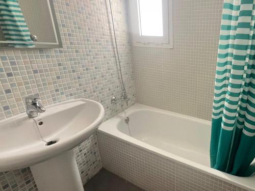 a white bathroom with a sink and a tub and a sink at Apartamentos Las Arenas 3000 in Alcossebre