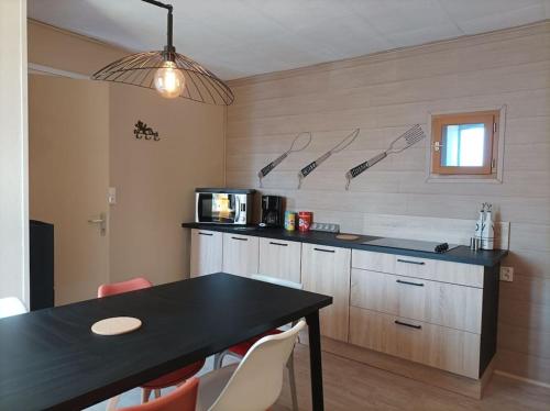 une cuisine avec un comptoir noir et une table avec des chaises dans l'établissement Côte & Mer, à Criel-sur-Mer