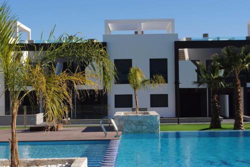 a swimming pool with palm trees in front of a building at La Zenia in Playas de Orihuela