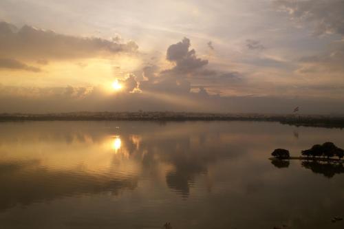 a sunset over a lake with the sun reflecting on the water at Hyderabad Marriott Hotel & Convention Centre in Hyderabad