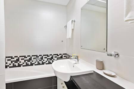 a white bathroom with a sink and a mirror at Silkhaus modern 2BDR with pool and gym near Reem Central Park in Abu Dhabi