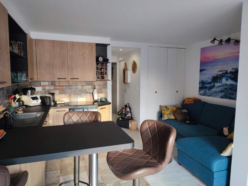 Il comprend une cuisine et un salon avec une table et un canapé bleu. dans l'établissement Magnifique appartement 6 pers climatisé grande terrasse vue port, au Cap d'Agde