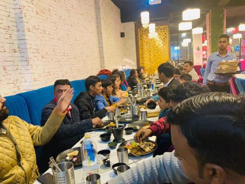 Sultānpur的住宿－Hotel Minitel INN，一群坐在餐桌上吃食物的人