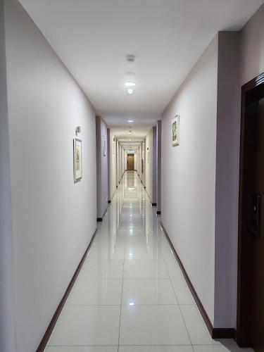 a long hallway with white walls and white tile floors at Hotel Prima in Sandakan