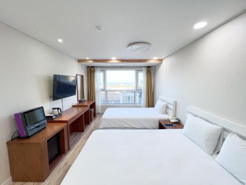 a hotel room with two beds and a tv at Hotel Sweet Castle Jeju Hamdeok in Jeju
