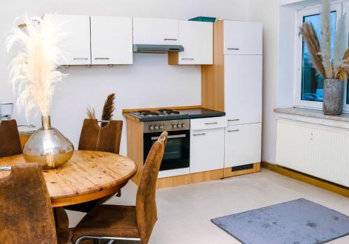 uma cozinha com armários brancos, uma mesa de madeira e um fogão em Rentarooms B em Oebisfelde