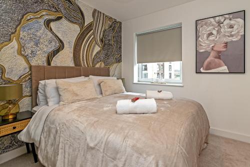 a bedroom with a bed with two towels on it at SUPERIOR AIRPORT SUITE, FREE Parking, Stylish, BALCONY, Two Bathrooms, Close To Airport, Station & Centre in Luton