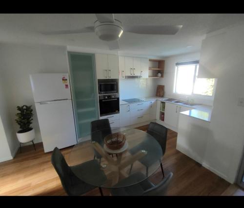 uma cozinha com uma mesa de vidro e cadeiras num quarto em Avondale Apartment em Lismore