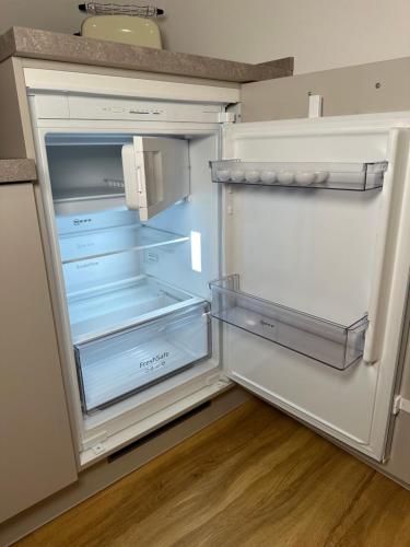 an empty refrigerator with its door open in a kitchen at Dümmerland Apartments in Lemförde
