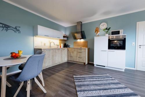 cocina con paredes azules y mesa con sillas en Racing-Apartment (Ferienwohnung) en Herresbach