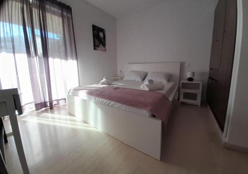 - une chambre blanche avec un lit et une grande fenêtre dans l'établissement Loveliest Place At AthensRiviera, à Vari