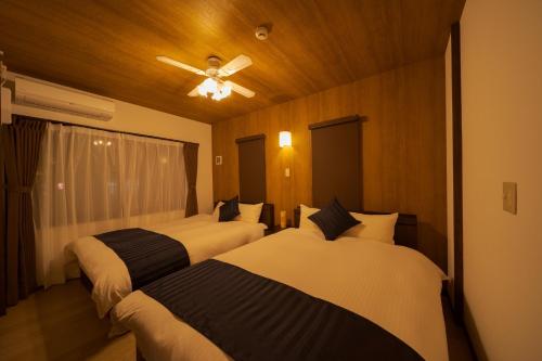 sypialnia z 2 łóżkami i wentylatorem sufitowym w obiekcie Tabi no yado Hanakeshiki Sakura 2nd floor - Vacation STAY 42969v w mieście Yufu