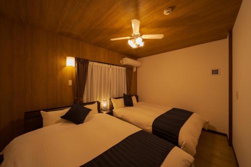 two beds in a room with a ceiling fan at Tabi no yado Hanakeshiki Botan 4th floor - Vacation STAY 43035v in Yufuin