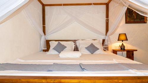 1 dormitorio con cama con dosel, sábanas y almohadas blancas en Ostello Surf Resort en Ahangama