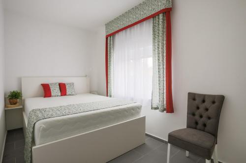 a small bedroom with a bed and a chair at 4seasons Apartments in Fonyód
