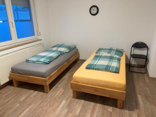 dwa łóżka w pokoju z zegarem na ścianie w obiekcie Unterkunft Heidenheim - kostenfreie Parkplätze, WLAN, eigene Küche, große Zimmer w mieście Heidenheim an der Brenz