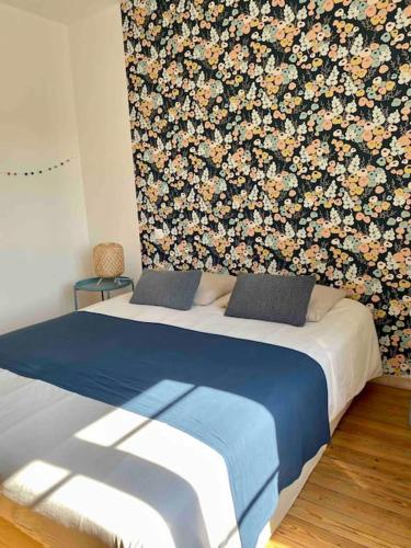 - une chambre avec un lit orné d'un mur fleuri dans l'établissement Maison de vacances, proche de la Baie de Somme, à Sailly-Flibeaucourt