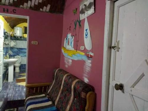 a bathroom with a couch against a pink wall at Azoz Nubian House in Aswan