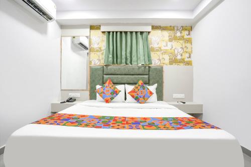 甘地訥格爾的住宿－FabHotel Grey Sky，卧室配有一张带彩色枕头的大型白色床。