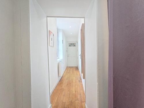 a hallway with white walls and a wooden floor at Le Régemortes, centre ville et proche du CNCS, avec services premium by PRIMO C0NCIERGERIE in Moulins