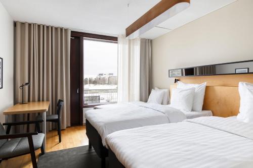 エスポーにあるオリジナル ソコス ホテル タピオラ ガーデン エスポーのベッド2台とデスクが備わるホテルルームです。