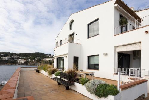 ein weißes Haus mit einer Terrasse und Wasser in der Unterkunft CASA SOL I PLATJA Calella Palafrugell con Parking in Calella de Palafrugell