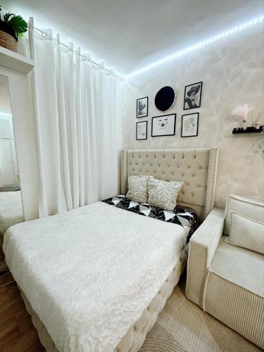 a white bedroom with a bed and a chair at Appartement proche stade de France et métro 12 in Saint-Denis
