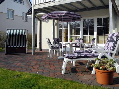 eine Terrasse mit einem Tisch, Stühlen und einem Sonnenschirm in der Unterkunft Bi de Park in Wyk auf Föhr