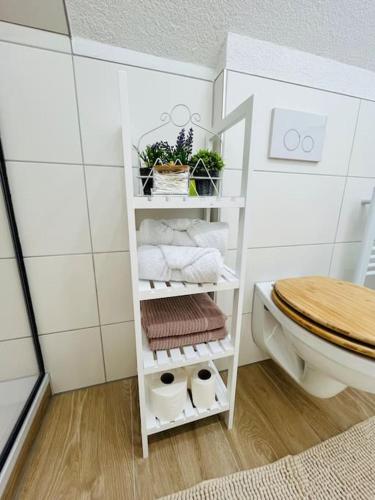a bathroom with a white shelf with towels and a toilet at Mia’sFerienwohnung/Monteurwohnung in Herborn