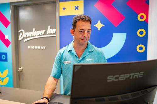 a man standing in front of a laptop computer at Howard Johnson by Wyndham Orlando Lake Buena Vista South in Kissimmee