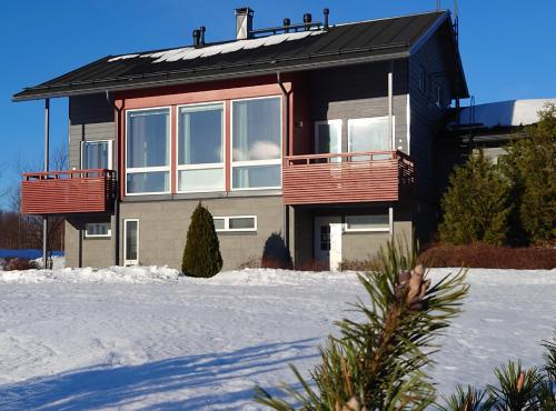 une maison avec des balcons rouges dans la neige dans l'établissement Villa Himalaja Himos, à Jämsä