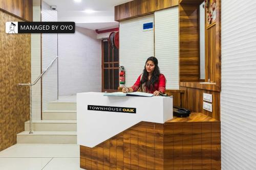 a woman sitting at a counter in a building at Towhouse Mumbai Airoli-Vashi - Formerly Blue Diamond in Turambhe