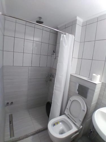 a white bathroom with a toilet and a sink at Oasis Hostel in Himare