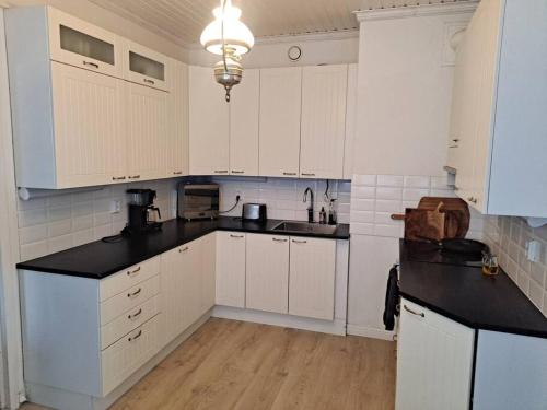 uma cozinha com armários brancos e um balcão preto em Spacious apartment in the city center em Vaasa