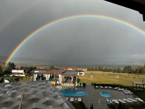 a rainbow in the sky over a pool at Family Hotel Eterno in Tsigov Chark