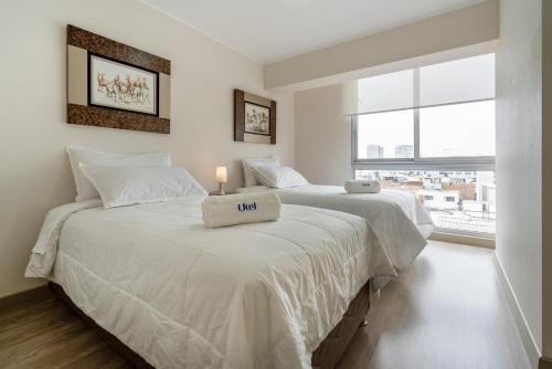 two beds in a white room with a window at Modern 1BR Loft close to the seawalk of Miraflores in Lima